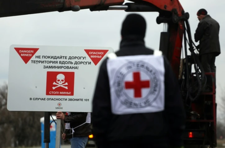 Des agents de la Croix-rouge installent des panneaux de prévention contre les mines "Danger de mines! Ne quittez pas la route!", sur le bord d'une route près du village de Berezové, dans la région de Donetsk, le 28 mars 2016