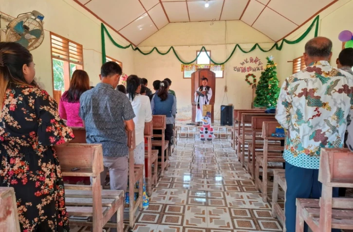Des villageois assistent à la messe de Noël à l'église protestante d'Angkola, dans le village d'Aek Ngadol, le 25 décembre 2025, dans la province de Sumatra touchée par des inondations et glissements de terrain meurtriers, en Indonésie
