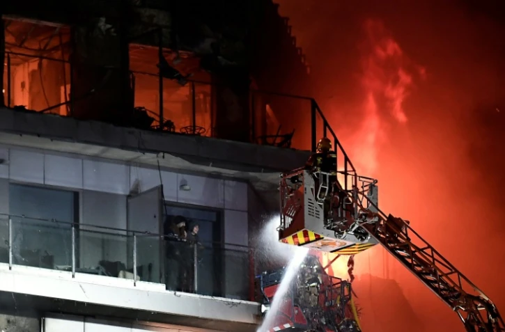 Deux résidents sur un balcon attendent d'être secourus par les pompiers lors d'un incendie dans un immeuble résidentiel à Valence, le 22 février 2024 en Espagne