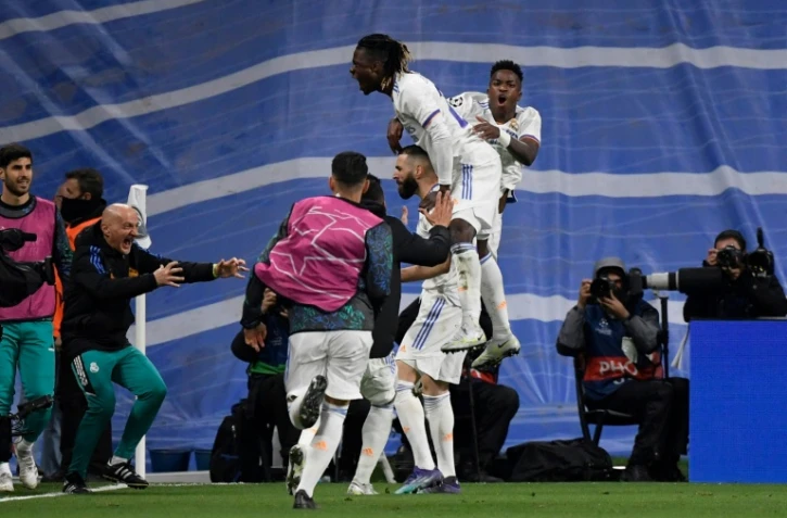 Real Madrid's French forward Karim Benzema célébré par ses coéquipiers après avoir réduit le score pour le Real (2-3) contre Chelsea à Madrid, le 12 avril 2022  