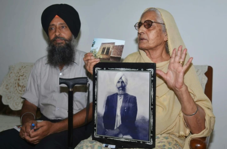 Sushwant Kaur, 78 ans, (d), assise à côté de son fils Jaswinder Singh (g), montre la photo de son défunt père, Sulkhan Singh, le 5 juillet 2017 à Amritsar, en Inde