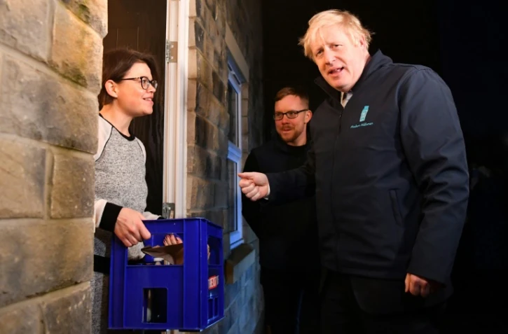Boris Johnson, en campagne pour les élections de jeudi, livre du lait à une famille de  Guiseley, dans le nord de l'Angleterre, le 11 décembre 2019