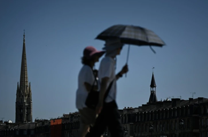 Des passants se protègent du soleil avec un parapluie à Bordeaux, le 5 juillet 2026 en Gironde, lors d'une vague de chaleur en France