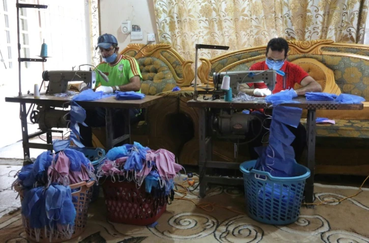 Asaad al-Saadi (g) travaille chez lui à Bagdad, le 3 avril 2020   avec son frère Mohammed après avoir transformé une chambre de la maison en un atelier de fabrication de masques de protection