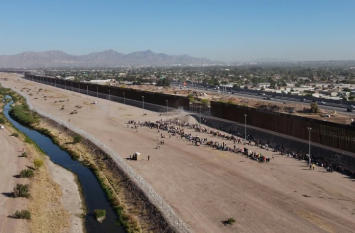 Des migrants attendent d'être pris en charge par la police aux frontières américaine près des rives du Rio Grande à Ciudad Juarez, au Mexique