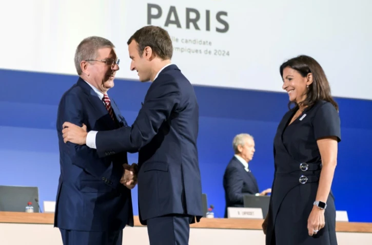 Le président Emmanuel Macron (c) serre la main du président du CIO à son arrivée au siège de l'instance à Lausanne pour la présentation de la candidature de Paris pour les JO-2024, le 11 juillet 2017  