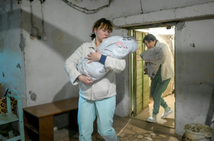 Des infirmières transportent des bébés dans un le sous-sol d'une maternité pendant une alerte aérienne à Mykolaïv, en Ukraine, le 14 mars 2022