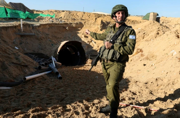 Un porte-parole de l'armée israélienne désigne lors d'une visite de presse l'entrée d'un tunnel dont les forces israéliennes affirment qu'il est "le plus grand" que le Hamas ait creusé, le 15 décembre 2023 près du point de passage d'Erez entre Israël et le nord de la bande de Gaza