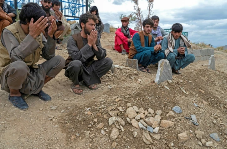 Des Afghans prient devant les tombes des victimes au lendemain d'un attentat à l'explosif dans une mosquée de Kaboul, le 18 août 2022