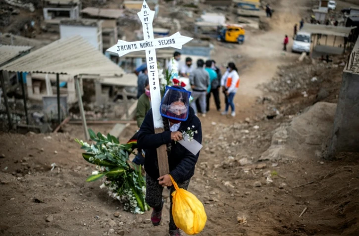 Une femme porte une croix lors des funérailles d'un proche au cimetière de Nueva Esperanza, près de Lima, le 30 mai 2020 au Pérou