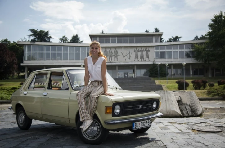 Jovana Stojiljkovic, une des dirigeantes du tour-opérateur Yugotour, assise sur le capot d'une "Zastava 101", devant le musée de la Yougoslavie, le 25 mai 2018 à Belgrade