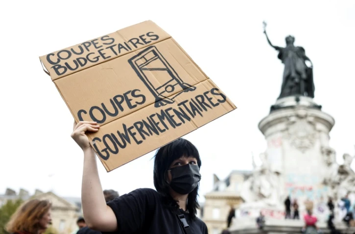 Une manifestante tient une pancarte sur laquelle on peut lire "Coupes budgétaires, coupes gouvernementales" lors d'une manifestation sur la place de la République, à Paris, le 10 septembre 2025