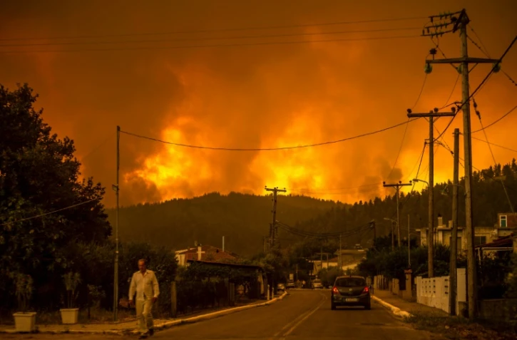 Un habitant marche le long d'une route alors qu'un incendie fait rage près du village de Gouves, sur l'île d'Eubée (Grèce), le 8 août 2021