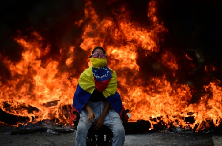 Un manifestant assis devant une barricade en flammes lors d'une manifestation à Caracas, le 24 avril 2017