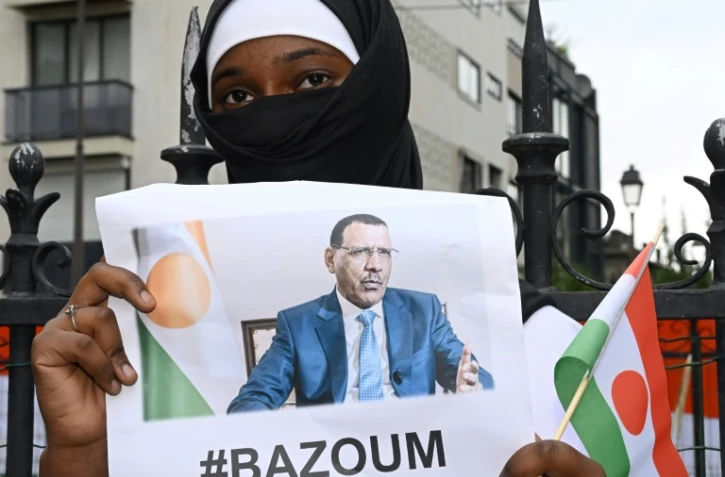 Une femme tient une photo du président nigérien déchu Mohammed Bazoum, détenu depuis le 26 juillet, devant l'ambassade du Niger à Paris le 5 août 2023