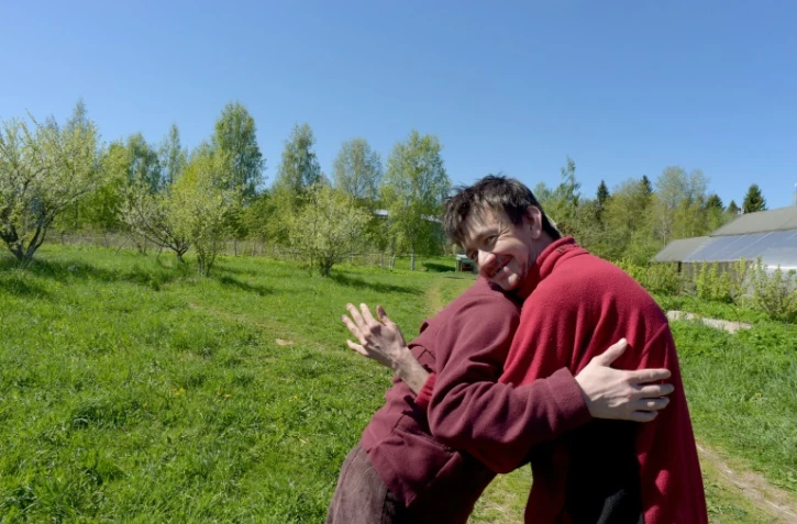 Svetlana, 35 ans, et Dima, 34 ans, se donnent l'accolade dans un champ de la ferme thérapeutique  près du village d'Aleksino (Russie), le 18 mai 2019

