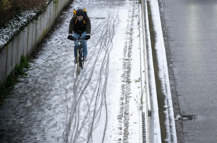 Un homme circule à vélo dans une rue enneigée le 8 janvier 2024 à Mulhouse, dans le Haut-Rhin