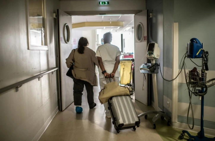 Aidée par une infirmière une patiente sort d'un hôpital parisien après y avoir été soignée contre la Covid-19, le 28 mai 2020