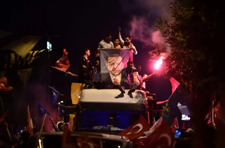 Des partisans du président turc réélu Recep Tayyip Erdogan brandissent des drapeaux turcs et une affiche à son effigie devant le siège du parti AKP, à Istanbul le 24 juin 2018