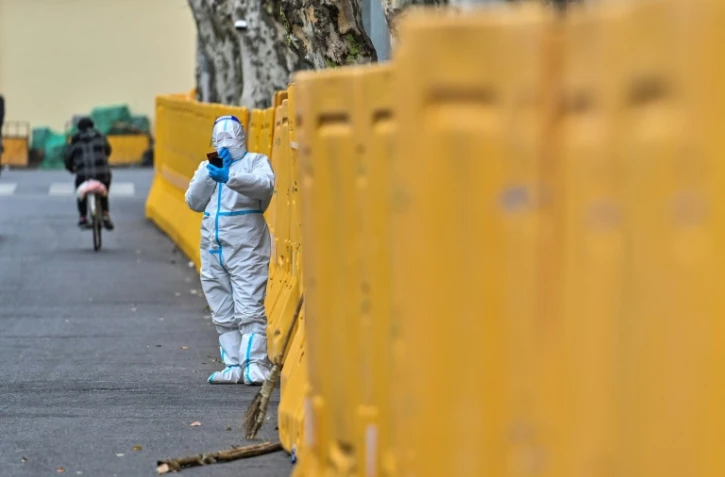 Un homme en tenue de protection devant une barrière érigée à Shanghai, où un confinement a été décrété pour lutter contre l'épidémie de Covid-19, le 31 mars 2022