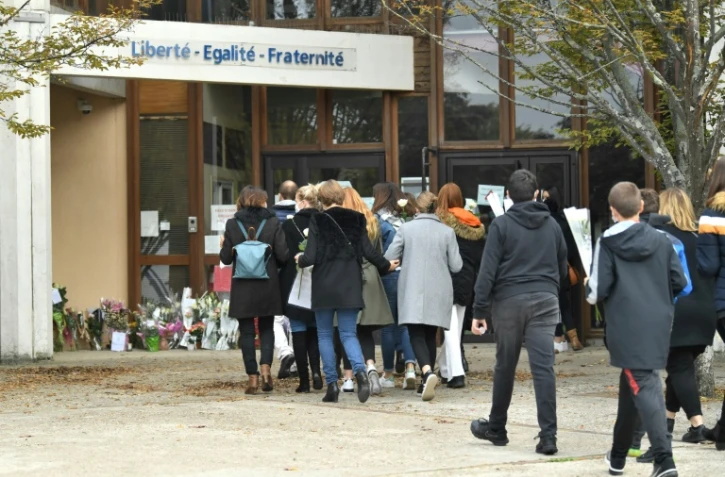 Adultes et enfants viennent déposer des fleurs devant l'école de Conflans-Sainte-Honorine, le 17 octobre 2020 au lendemain de la décapitation d'un des professeurs