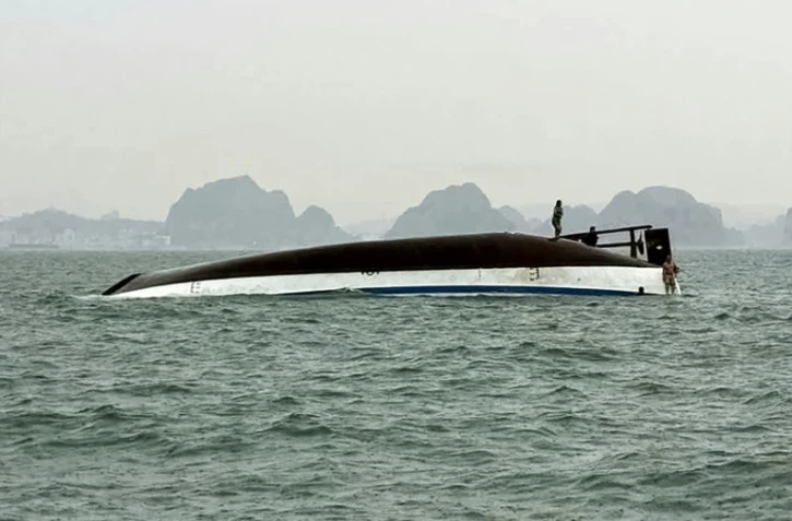 Un homme se tient sur un bateau touristique qui a chaviré dans la baie d'Halong, le 19 juillet 2025