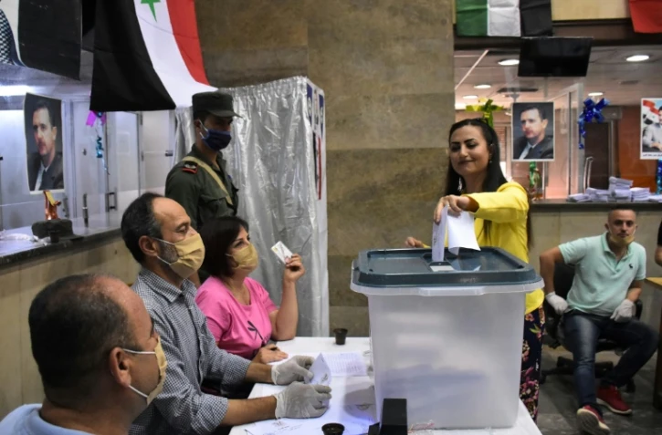 Une femme glisse son bulletin  dans un bureau de vote de la ville d?Alep, dans le nord de la Syrie, le 19 juillet 2020 à l'occasion des législatives syriennes