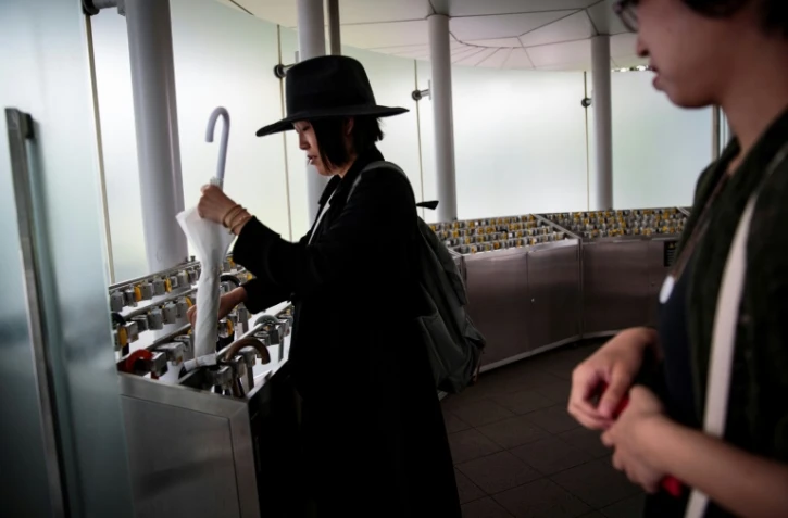 Une femme place son parapluie dans une consigne au Centre national des Arts à Tokyo le 4 septembre 2017 