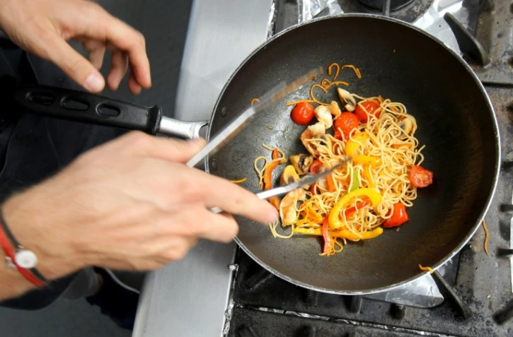 Le Français Romain Grosjean prépare un plat de pâtes lors de son temps libre, sur le circuit Hermanos Rodriguez de Mexico, en marque du GP du Mexique, le 25 octobre 2018
