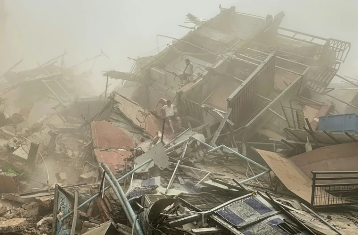 Des personnes fouillent les décombres d'un bâtiment détruit par un puissant séisme, le 28 mars 2025 à Mandalay