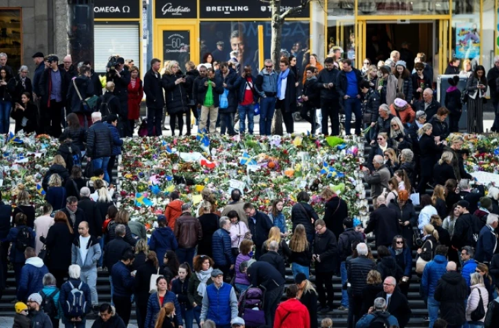 Des personnes se rassemblent devant des fleurs pour rendre hommage aux victimes de l'attentat de Stockholm le 9 avril 2017