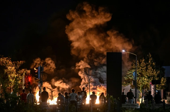 Des passants regardent des pneus en feu sur une rue à Bordeaux, le 29 juin, 2023