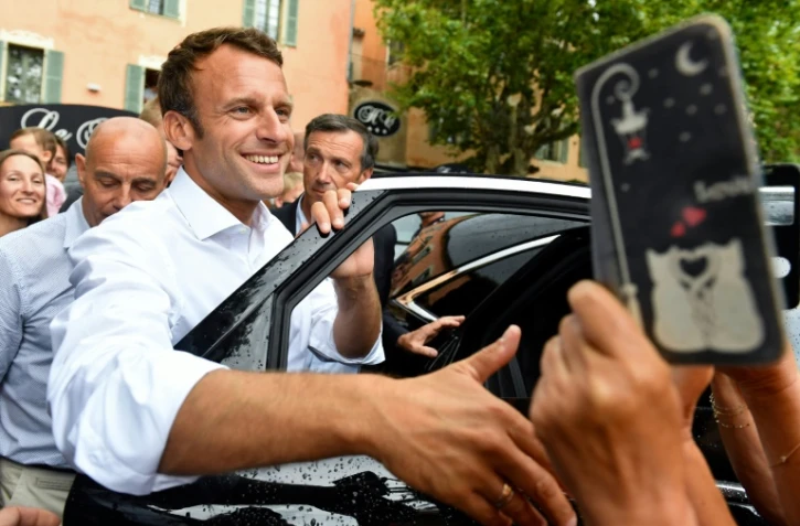Le président Emmanuel Macron salue la foule après s'être entretenu avec le maire de la commune de Bormes-les-Mimosas (Var), le 27 juillet 2019