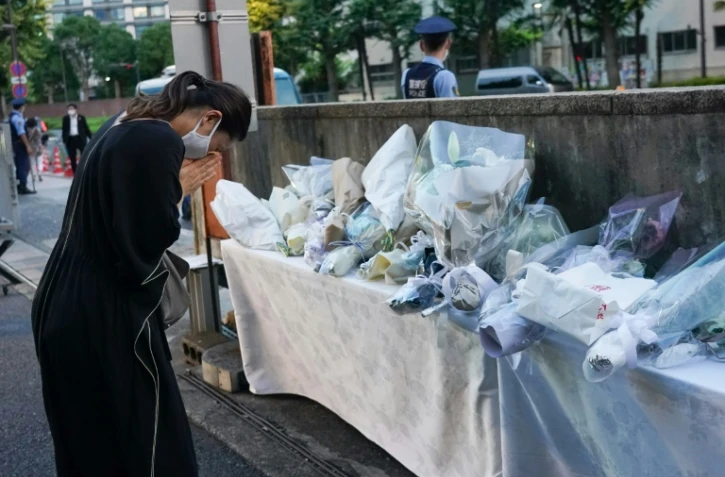 Une femme se recueille devant le siège du Parti libéral-démocrate (PLD) à Tokyo le 10 juillet 2022, après l'assassinat de l'ancien Premier ministre Shinzo Abe