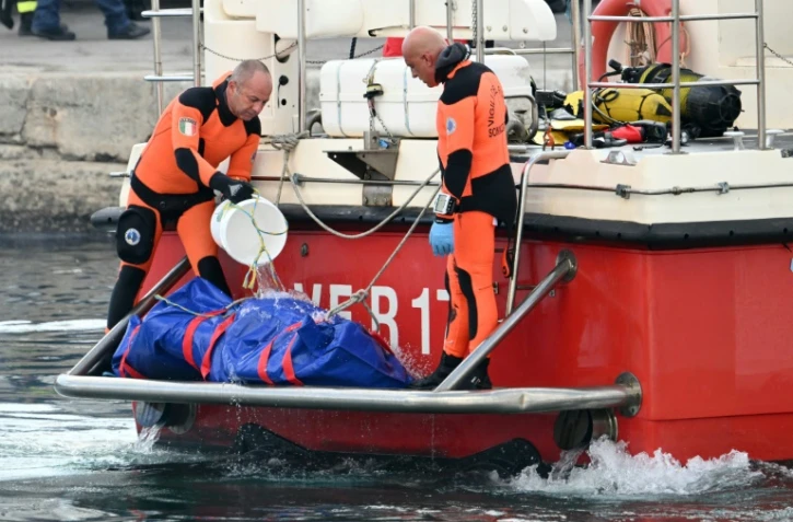 Retour au port italien de Porticello, en Sicile, des plongeurs recherchant les personnes portées disparues dans l'épave du yacht de luxe de Mike Lynch, un sac mortuaire à l’arrière du bateau, le 22 août 2024.