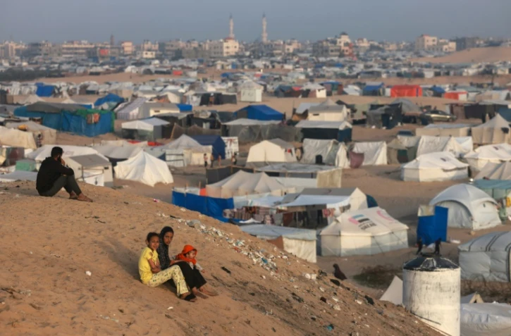 Des enfants palestiniens sont assis non loin d'un camp de fortune où des déplacés palestiniens ont trouvé refuge le 30 mars 2024