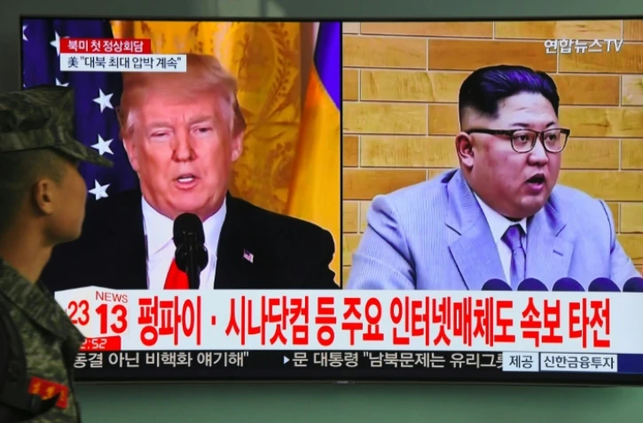 Un soldat sud-coréen regarde les portraits de Donald Trump et Kim Jong Un à la télévision, le 9 mars 2018