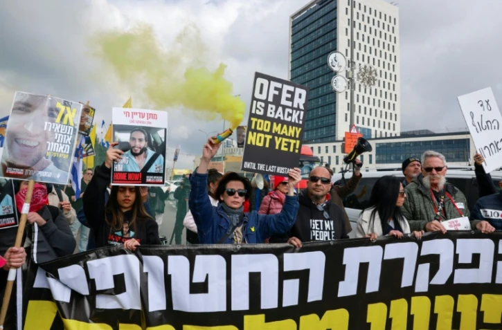 Des manifestants israéliens brandissent pancartes et banderoles devant le bureau du Premier ministre à Jérusalem, appelant à continuer de mettre en application l'accord de trêve à Gaza afin de ramener tous les otages encore captifs, le 11 février 2025
