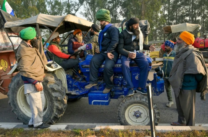Des agriculteurs sur un tracteur réclament un prix minimum pour leurs récoltes, le 15 février 2024 à Shambhu en Inde