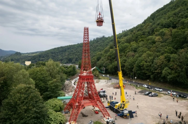 Des ouvriers installent la flèche d'une réplique à l'échelle 1/10e de la Tour Eiffel, construite par l'entrepreneur alsacien Jean-Claude Fassler, à Sainte-Croix-aux-Mines, dans le Haut-Rhin, le 26 août 2025