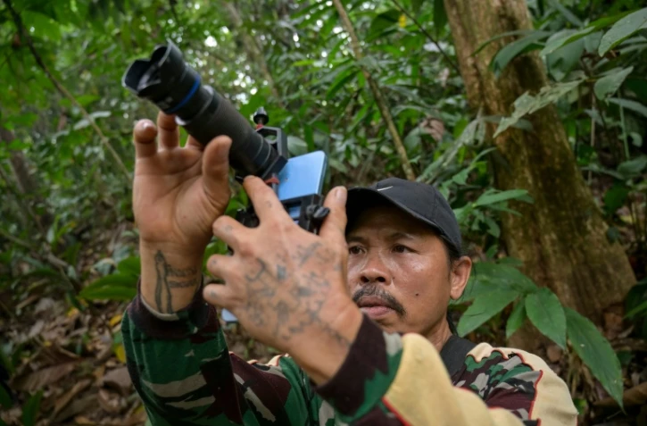 Octavius, villageois indonésien et ancien braconnier, utilise un téléphone portable équipé d’un téléobjectif pour prendre des photos d’animaux sauvages dans une forêt près du village de Labian, à Kapuas Hulu, à Bornéo, le 2 septembre 2026