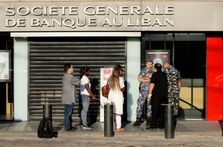 Des membres des forces de l'ordre contrôlant l'entrée d'une succursale d'une banque à Beyrouth, le 19 novembre 2019