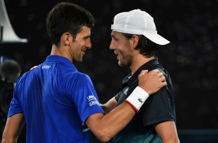 Le Serbe Novak Djokovic (g) congratule le Français Lucas Pouille, éliminé par le Croate en demi-finales de l'Open d'Australie, le 25 janvier 2019 à Melbourne  