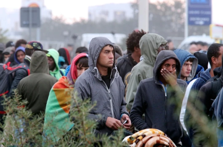 Des migrants attendent de monter dans des bus lors de l'évacuation de la "Jungle" le 26 octobre 2016 à Calais