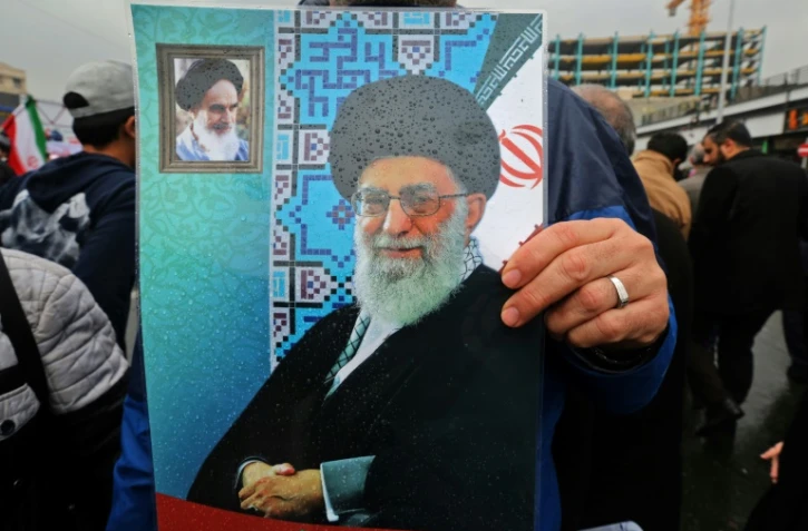 Un Iranien brandit une affiche avec le portrait du guide suprême Ali Khamenei (centre) et de l'ayatollah Rouhollah Khomeiny, père fondateur de la République islamique (en haut à gauche), lors du 40e anniversaire de la Révolution islamique à Téhéran, le 11 février 2019