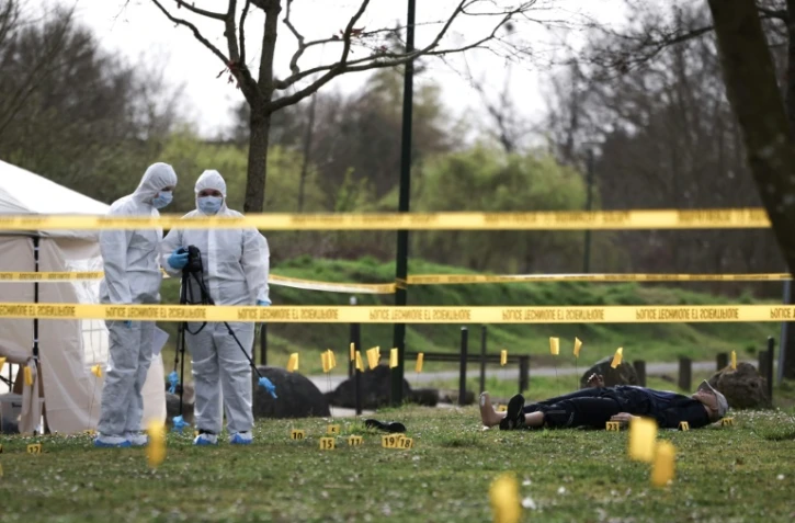Des étudiants de l'école CY Forensic prennent des photos sur la reconstitution d'une scène de crime lors d'une session de formation à Neuville-sur-Oise, au nord-est de Paris, le 21 mars 2025 dans le Val d'Oise