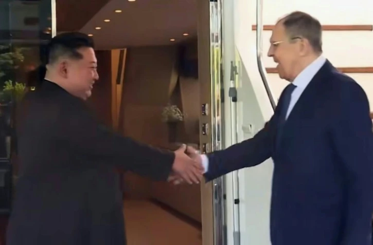 Capture d'écran tirée d'une vidéo fournie par le ministère russe des Affaires étrangères montrant le ministre russe des Affaires étrangères Sergueï Lavrov (à droite) serrant la main du leader nord-coréen Kim Jong Un (à gauche) à Wonsan, le 12 juillet 2025