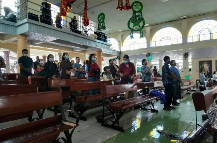 Des fidèles assistent à la messe de Noël, dans leur église encore inondée, le 25 décembre 2021 à Alegria, plus d'une semaine après le passage du typhon Rai aux Philippines