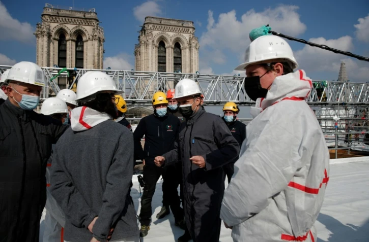 Le président Emmanuel Macron (C) sur le toit de Notre-Dame le 15 avril 2021 à Paris 