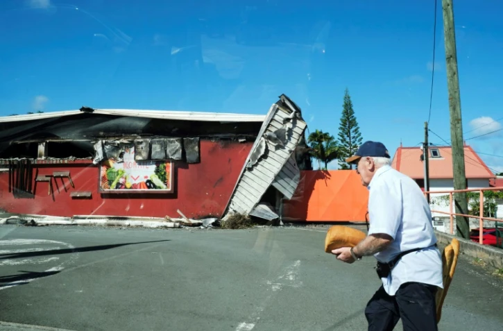 Un homme passe devant un supermarché endommagé à Nouméa, en Nouvelle-Calédonie, le 24 mai 2024